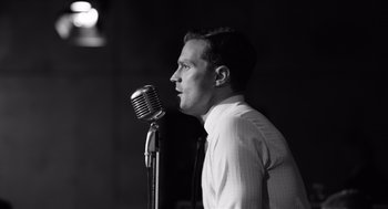 Movie still from “Belfast” (2021), directed by Kenneth Branagh – A black and white photo of a man with a microphone; Close Up shot, Low angle