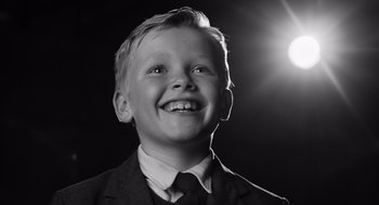 Movie still from “Belfast” (2021), directed by Kenneth Branagh – A boy in a suit and tie smiling for the camera; Close Up shot, Low angle