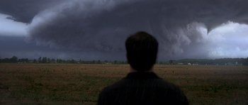 Movie still from “Take Shelter” (2011), directed by Jeff Nichols – A man standing in the middle of a field under a cloudy sky; Extreme Wide shot, Over the shoulder angle