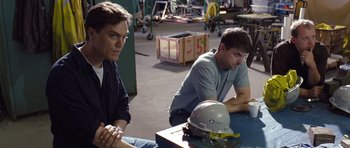 Movie still from “Take Shelter” (2011), directed by Jeff Nichols – Two men sitting on a table in a warehouse; Medium shot, High angle