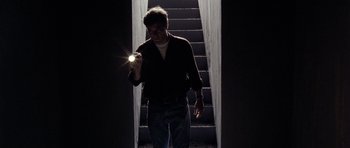 Movie still from “Take Shelter” (2011), directed by Jeff Nichols – A man holding a flashlight in front of stairs; Medium shot, Low angle