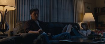 Movie still from “Take Shelter” (2011), directed by Jeff Nichols – A man sitting on a couch holding a remote control; Medium shot, Low angle