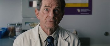 Movie still from “Take Shelter” (2011), directed by Jeff Nichols – An older man wearing a lab coat and a tie; Close Up shot, Over the shoulder angle