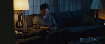 Movie still from “Take Shelter” (2011), directed by Jeff Nichols – A man sitting on top of a couch in a living room; Medium shot, High angle
