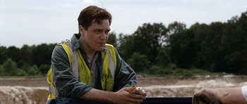 Movie still from “Take Shelter” (2011), directed by Jeff Nichols – A man sitting on the back of a pick up truck eating a hot dog; Medium shot, Low angle
