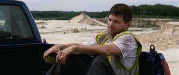 Movie still from “Take Shelter” (2011), directed by Jeff Nichols – A man sitting on top of a truck in a field; Medium shot, Over the shoulder angle
