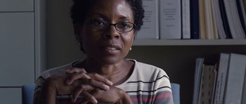 Movie still from “Take Shelter” (2011), directed by Jeff Nichols – A person wearing glasses with their hands clasped; Close Up shot, Over the shoulder angle