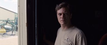 Movie still from “Take Shelter” (2011), directed by Jeff Nichols – A man in a tan shirt is standing in a dark room; Close Up shot, Low angle