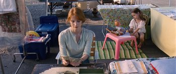 Movie still from “Take Shelter” (2011), directed by Jeff Nichols – A woman sitting at a table holding a stack of money; Medium shot, High angle