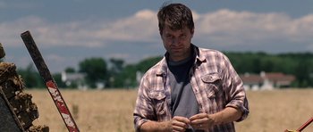 Movie still from “Take Shelter” (2011), directed by Jeff Nichols – A person standing in a field near a tree; Medium shot, Over the shoulder angle