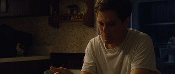 Movie still from “Take Shelter” (2011), directed by Jeff Nichols – A man sitting at a table looking at something on his hand; Close Up shot, Low angle