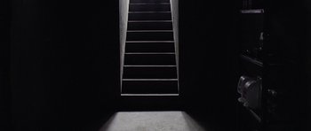 Movie still from “Take Shelter” (2011), directed by Jeff Nichols – A dark room with stairs leading up to a door; Extreme Wide shot, Low angle