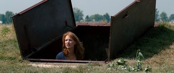 Movie still from “Take Shelter” (2011), directed by Jeff Nichols – A red haired woman sitting in an open metal box; Medium shot, Low angle