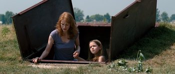 Movie still from “Take Shelter” (2011), directed by Jeff Nichols – A woman and a girl sitting on the ground; Medium shot, High angle