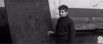 Movie still from “The 400 Blows” (1959), directed by François Truffaut – A young man standing in front of a chalkboard; Medium shot, High angle