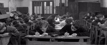 Movie still from “The 400 Blows” (1959), directed by François Truffaut – A group of people sitting at a table writing on paper; Medium shot, High angle