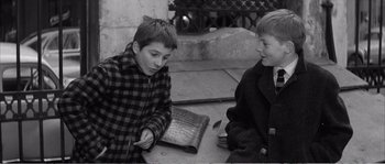 Movie still from “The 400 Blows” (1959), directed by François Truffaut – Two young boys sitting next to each other on the ground; Medium shot, High angle