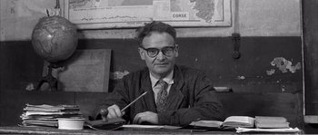Movie still from “The 400 Blows” (1959), directed by François Truffaut – An older man sitting at a table with a pen and a wooden handle; Medium shot, Low angle