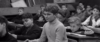 Movie still from “The 400 Blows” (1959), directed by François Truffaut – Black and white photograph of a young boy in a classroom; Medium shot, High angle