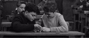 Movie still from “The 400 Blows” (1959), directed by François Truffaut – Two young boys are playing a game with a metal object; Medium shot, High angle