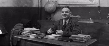 Movie still from “The 400 Blows” (1959), directed by François Truffaut – An older man sitting at a desk in front of a globe; Medium shot, High angle