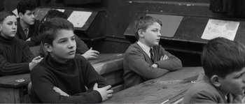Movie still from “The 400 Blows” (1959), directed by François Truffaut – Two young men sitting at a table with their arms crossed; Medium shot, High angle