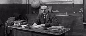 Movie still from “The 400 Blows” (1959), directed by François Truffaut – An old black and white photo of a man sitting at a desk; Medium shot, High angle