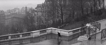 Movie still from “The 400 Blows” (1959), directed by François Truffaut – A person running in the rain near a building; Extreme Wide shot, High angle