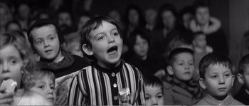 Movie still from “The 400 Blows” (1959), directed by François Truffaut – A young boy singing into a microphone in front of a crowd; Medium shot, High angle