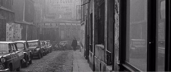 Movie still from “The 400 Blows” (1959), directed by François Truffaut – An old black and white photo of a man walking down a street; Wide shot, High angle