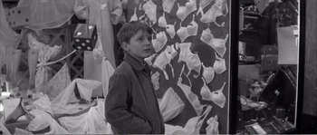 Movie still from “The 400 Blows” (1959), directed by François Truffaut – A young boy standing in front of a wall of paper; Medium shot, Over the shoulder angle