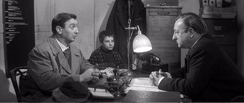 Movie still from “The 400 Blows” (1959), directed by François Truffaut – A group of people sitting around a table; Medium shot, Over the shoulder angle