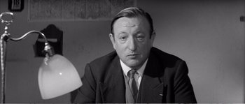 Movie still from “The 400 Blows” (1959), directed by François Truffaut – An old black and white photo of a man in a suit; Close Up shot, High angle
