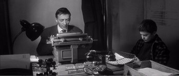 Movie still from “The 400 Blows” (1959), directed by François Truffaut – A black and white photo of a man typing on a typewriter; Medium shot, High angle
