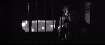 Movie still from “The 400 Blows” (1959), directed by François Truffaut – A man sitting behind bars in front of a window; Close Up shot, Over the shoulder angle