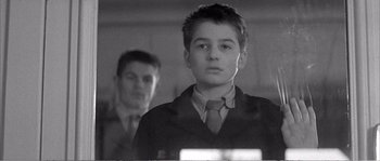 Movie still from “The 400 Blows” (1959), directed by François Truffaut – A young boy wearing a suit and tie in front of another man; Close Up shot, Low angle