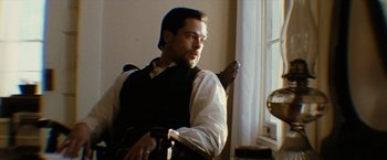 Movie still from “The Assassination of Jesse James by the Coward Robert Ford” (2007), directed by Andrew Dominik – A man sitting in front of a window in a chair; Medium shot, Low angle