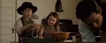 Movie still from “The Assassination of Jesse James by the Coward Robert Ford” (2007), directed by Andrew Dominik – A little girl sitting at a table in front of a bowl of food; Medium shot, Low angle