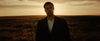 Movie still from “The Assassination of Jesse James by the Coward Robert Ford” (2007), directed by Andrew Dominik – A man in a suit standing in front of a field; Close Up shot, Low angle