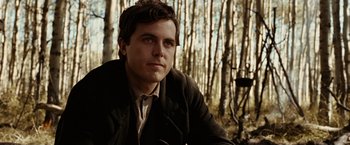 Movie still from “The Assassination of Jesse James by the Coward Robert Ford” (2007), directed by Andrew Dominik – A man in a jacket is sitting in the woods; Close Up shot, Low angle