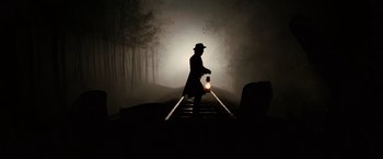 Movie still from “The Assassination of Jesse James by the Coward Robert Ford” (2007), directed by Andrew Dominik – A man holding a lantern standing on a train track in the dark; Wide shot, Low angle