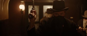 Movie still from “The Assassination of Jesse James by the Coward Robert Ford” (2007), directed by Andrew Dominik – A man holding a gun in a dimly - lit room; Close Up shot, Low angle