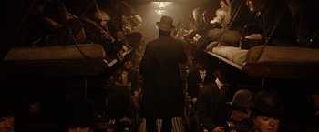 Movie still from “The Assassination of Jesse James by the Coward Robert Ford” (2007), directed by Andrew Dominik – A group of people sitting in a room; Wide shot, High angle
