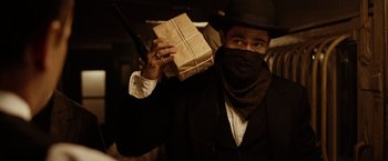 Movie still from “The Assassination of Jesse James by the Coward Robert Ford” (2007), directed by Andrew Dominik – A man holding a package in his hand; Medium shot, Low angle