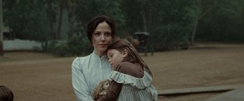 Movie still from “The Assassination of Jesse James by the Coward Robert Ford” (2007), directed by Andrew Dominik – A woman and a girl are holding a doll; Close Up shot, Over the shoulder angle