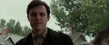 Movie still from “The Assassination of Jesse James by the Coward Robert Ford” (2007), directed by Andrew Dominik – A man in a suit and tie standing in front of a tree; Close Up shot, Low angle
