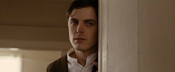 Movie still from “The Assassination of Jesse James by the Coward Robert Ford” (2007), directed by Andrew Dominik – A man standing in front of a door looking to his left; Close Up shot, Low angle
