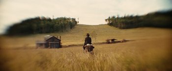 Movie still from “The Assassination of Jesse James by the Coward Robert Ford” (2007), directed by Andrew Dominik – A man riding a horse through a field of tall grass; Extreme Wide shot, High angle