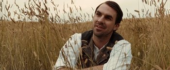 Movie still from “The Assassination of Jesse James by the Coward Robert Ford” (2007), directed by Andrew Dominik – A man sitting in a field of tall brown grass; Close Up shot, Over the shoulder angle