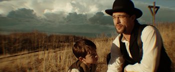 Movie still from “The Assassination of Jesse James by the Coward Robert Ford” (2007), directed by Andrew Dominik – A man and a young boy standing in a field; Close Up shot, Over the shoulder angle